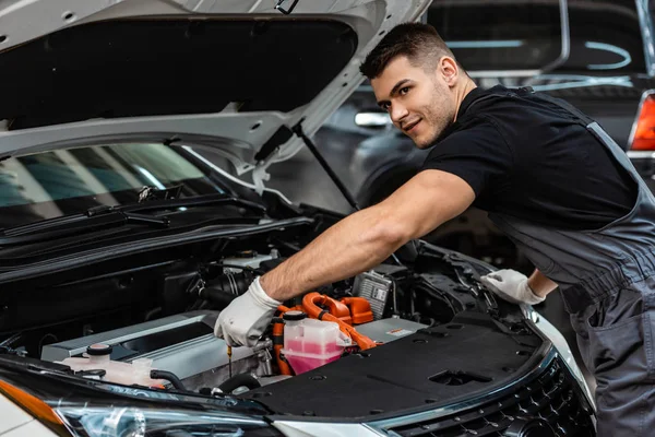 Gutaussehender Mechaniker überprüft den Ölstand des Motors und schaut weg — Stockfoto