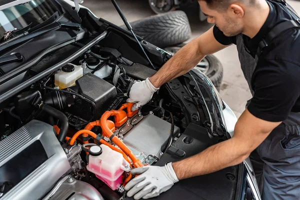 Joven mecánico que inspecciona el compartimiento del motor del coche - foto de stock