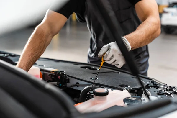 Teilansicht des Mechanikers, der den Ölstand des Motors mit Messstab überprüft — Stockfoto