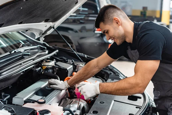 Chequeo mecánico sonriente nivel de aceite del motor con varilla de inmersión - foto de stock