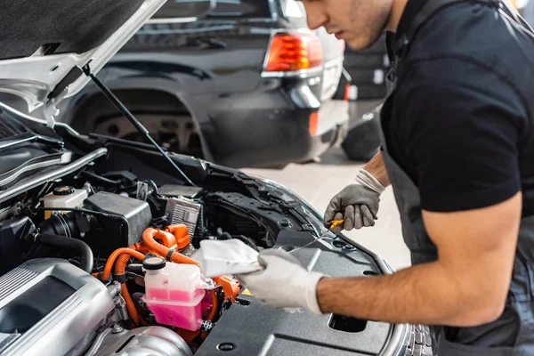 Partial view of mechanic wiping oil dipstick with rag near car engine compartment — Stock Photo