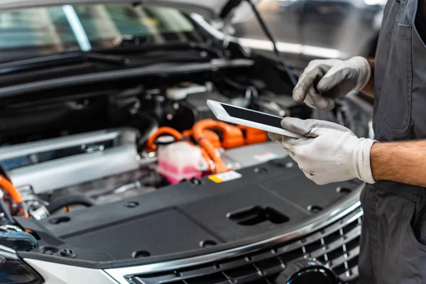 Partial view of mechanic using digital tablet near car engine compartment — Stock Photo