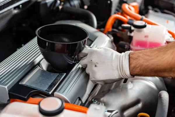 Cropped view of mechanic holding oil funnel near car engine — Stock Photo
