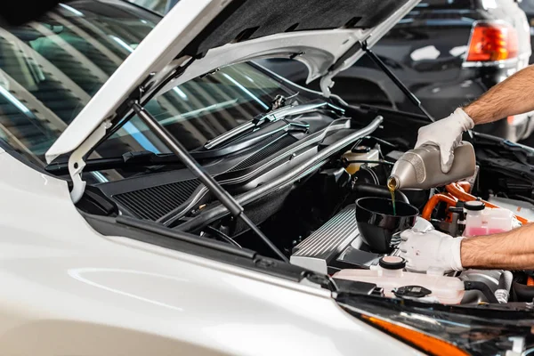 Partial view of mechanic pouring motor oil at car engine — Stock Photo