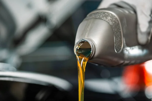 Partial view of mechanic pouring motor oil from bottle — Stock Photo