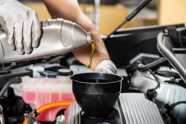 Vue partielle du mécanicien versant l'huile moteur au moteur de voiture — Photo de stock