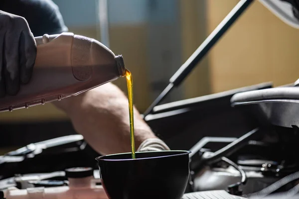 Vue partielle du mécanicien versant l'huile moteur au moteur de voiture — Photo de stock