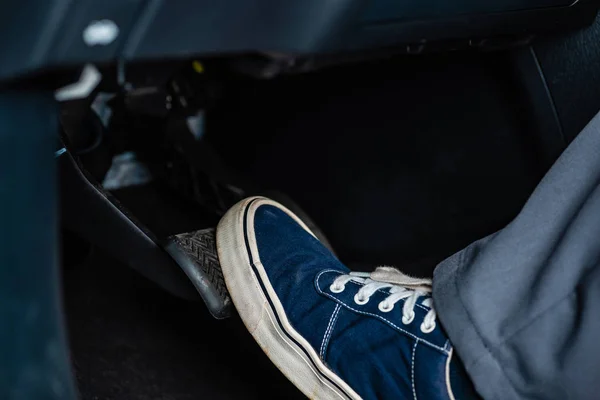 Teilansicht des Mechanikers in Turnschuhen, der im Auto auf das Bremspedal tritt — Stockfoto