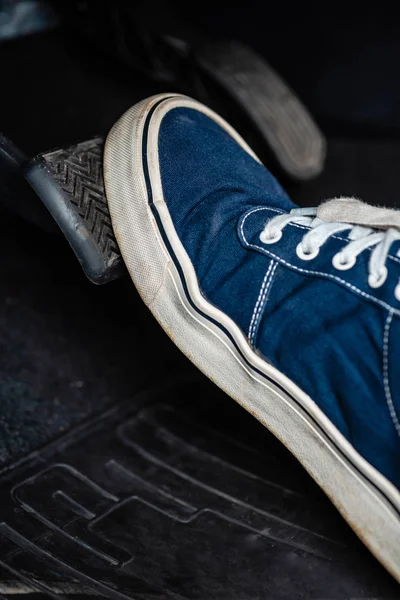 Partial view of mechanic in sneakers pressing brake pedal in car — Stock Photo