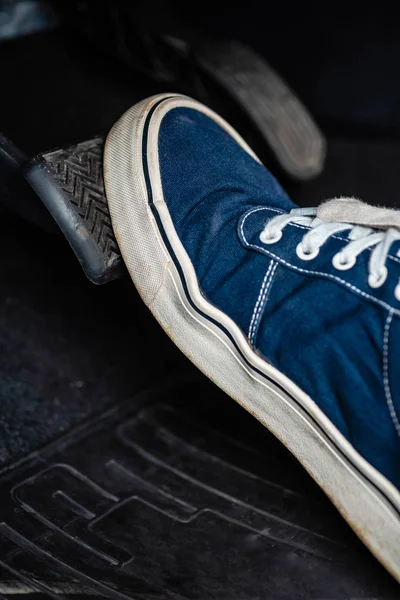 Vue partielle du mécanicien en baskets appuyant sur la pédale de frein dans la voiture — Photo de stock