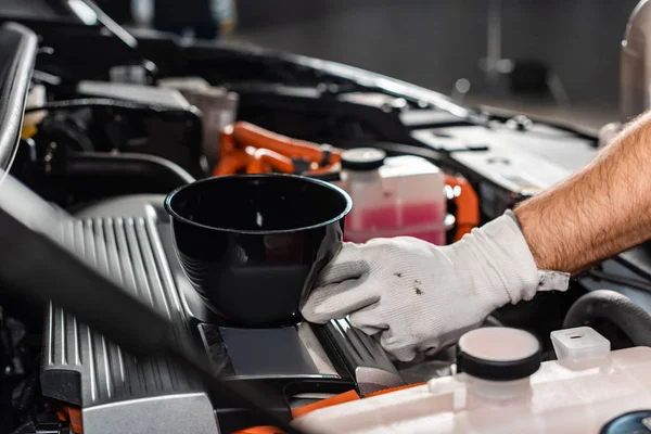 Cropped view of mechanic holding oil funnel near car engine — Stock Photo