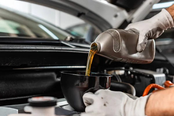 Partial view of mechanic pouring motor oil at car engine — Stock Photo