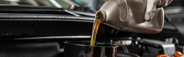 Partial view of mechanic pouring machine oil at car engine, panoramic shot — Stock Photo