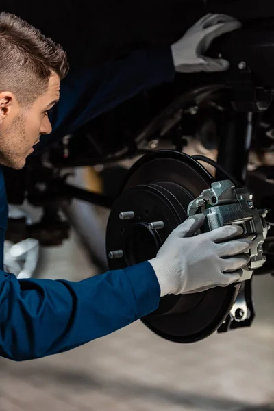 Young mechanic fixing brake pad on disc brakes — Stock Photo