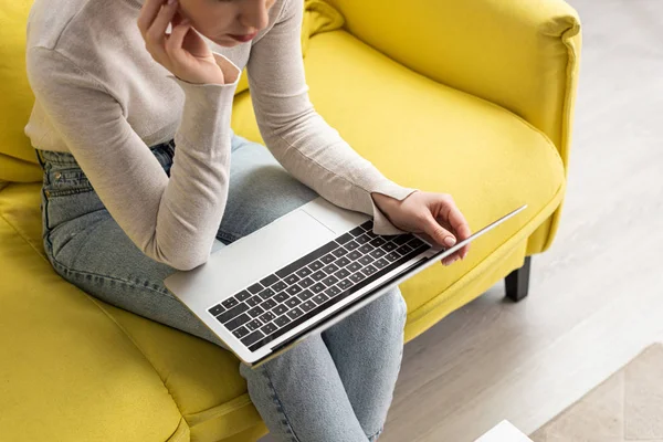 Vista ritagliata di ragazza che utilizza il computer portatile sul divano a casa — Foto stock