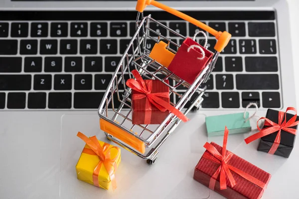 Top view of toy gift boxes with cart on laptop — Stock Photo