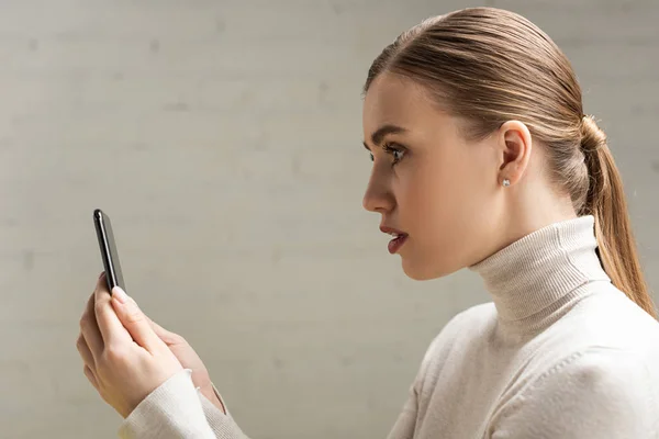 Side view of attractive woman holding smartphone — Stock Photo