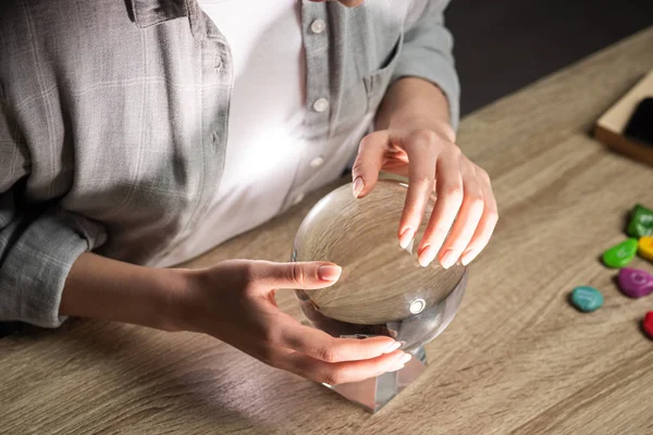 Cropped view of astrologer using crystal ball on wooden table — Stock Photo