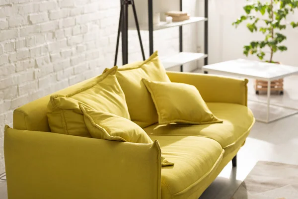 Canapé confortable jaune avec lumière du soleil dans le salon — Photo de stock