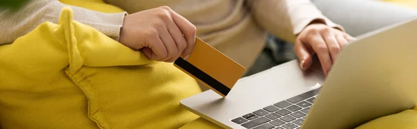 Vue recadrée d'une femme tenant une carte de crédit et utilisant un ordinateur portable, prise de vue panoramique — Photo de stock