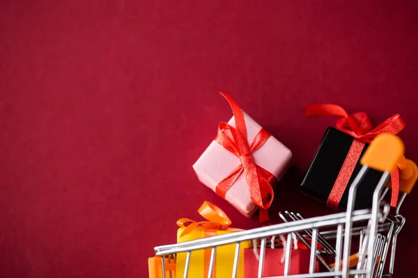 Vista superior de los regalos de juguete en el carro sobre fondo rojo con espacio de copia - foto de stock