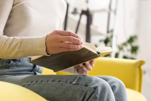 Ausgeschnittene Ansicht einer Frau, die zu Hause auf der Couch Buch liest — Stockfoto