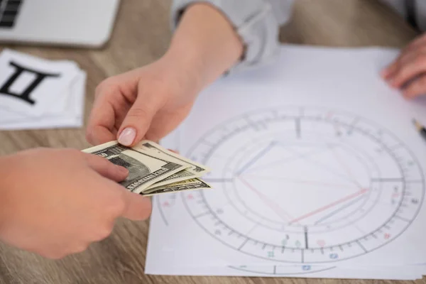 Cropped view of man paying to astrologer with natal chart on table — Stock Photo