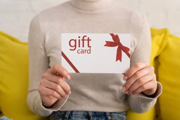 Cropped view of young woman showing gift card — Stock Photo