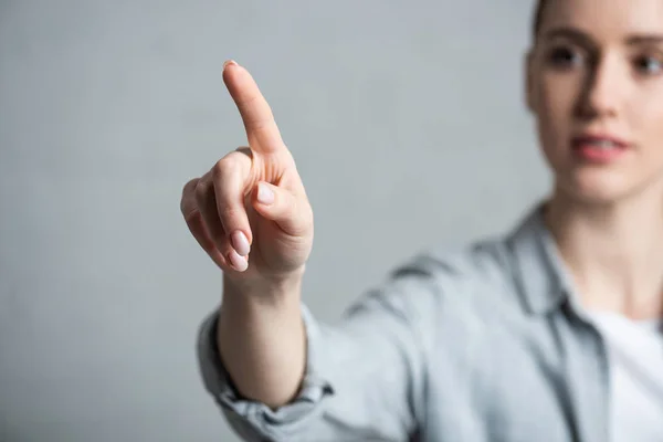 Enfoque selectivo de la mujer señalando con el dedo aislado en gris - foto de stock