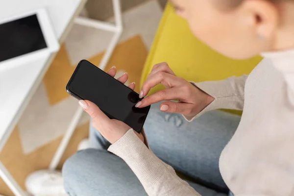 Enfoque selectivo de la niña usando teléfono inteligente con pantalla en blanco en el sofá - foto de stock