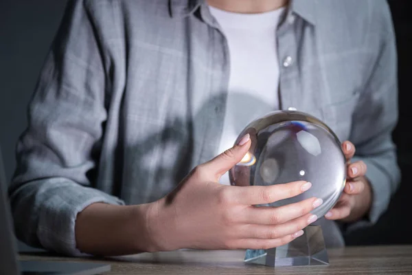 Cropped view of woman using crystal ball on wooden table — Stock Photo