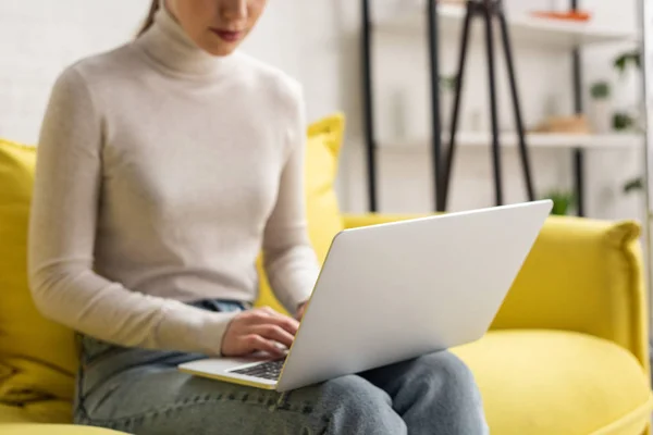 Cropped view of freelancer using laptop on sofa at home — Stock Photo