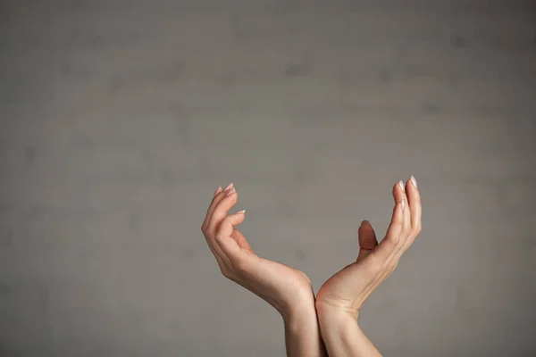 Vista recortada de la mujer haciendo gestos con las manos sobre fondo gris - foto de stock