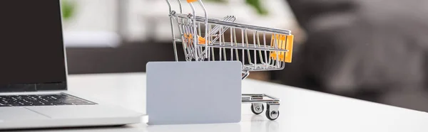 Vue panoramique de la carte de crédit, ordinateur portable et chariot à jouets sur la table — Photo de stock