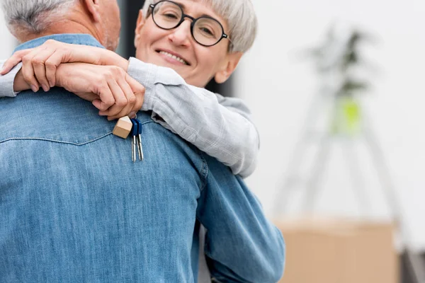 Vista ritagliata della donna sorridente che tiene le chiavi della nuova casa e abbraccia l'uomo maturo — Foto stock