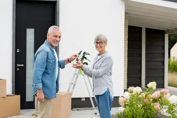 Зрелый мужчина вручает ключи от нового дома улыбчивой женщине — стоковое фото