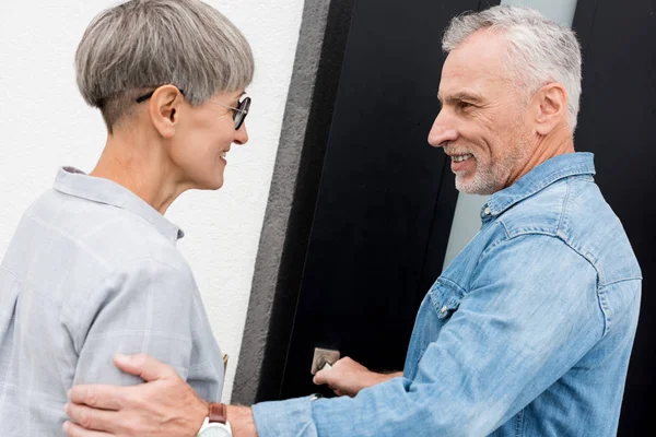 Mature man looking at woman and entering to new house — Stock Photo
