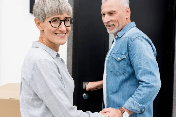 Älterer Mann blickt lächelnde Frau an und betritt neues Haus — Stockfoto