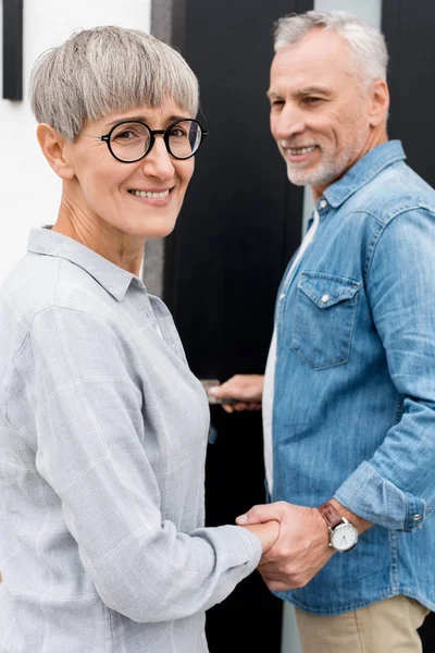 Mature man looking at smiling woman and entering to new house — Stock Photo