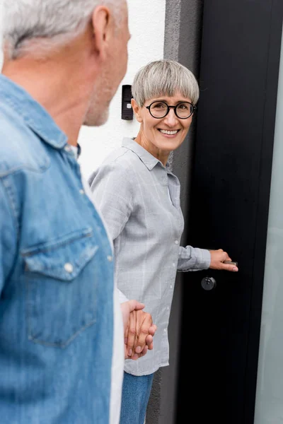 Vue recadrée de mature homme regardant femme souriante près de nouvelle maison — Photo de stock