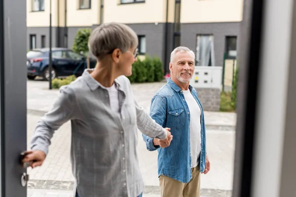 Femme tenant la main avec l'homme et entrant dans une nouvelle maison — Photo de stock