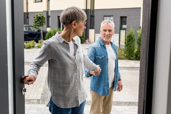 Woman holding hands with man and entering to new house — Stock Photo