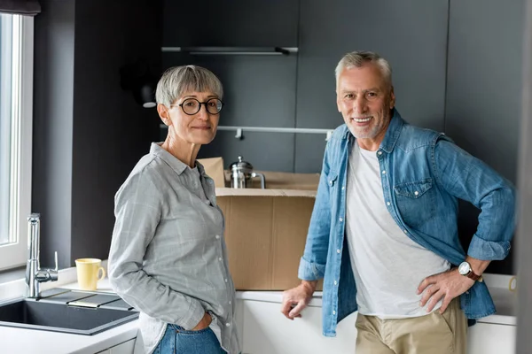 Uomo e donna sorridente guardando la fotocamera in una nuova casa — Foto stock