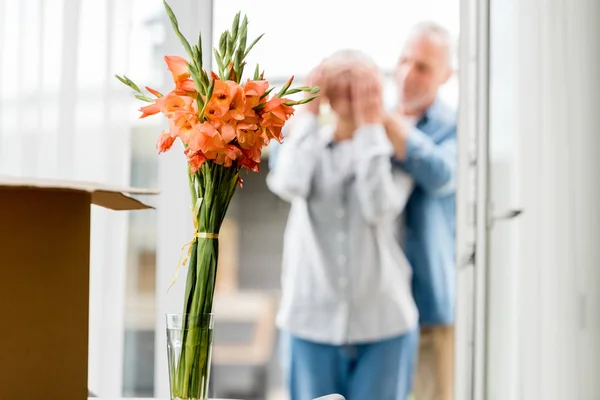 Selective focus of bouquet and mature couple in new house on background — Stock Photo