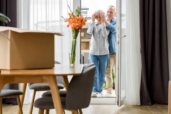 Enfoque selectivo del hombre sonriente oscurecimiento de la cara de la mujer en la nueva casa - foto de stock