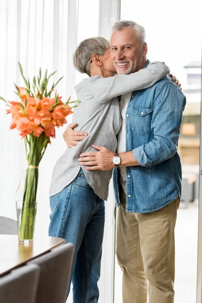 Mujer madura abrazando sonriente y guapo hombre en nueva casa - foto de stock