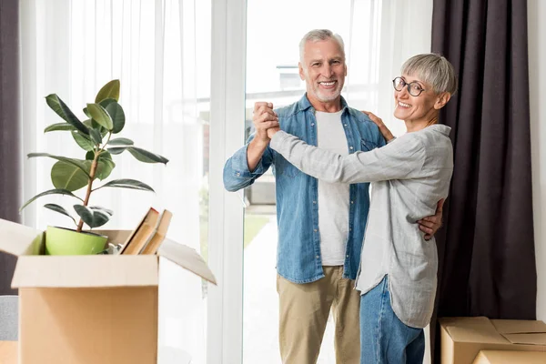 Homme mature et femme souriante dansant dans une nouvelle maison — Photo de stock