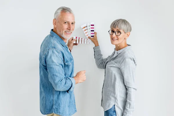 Mature man and woman with palette looking at camera in new house — Stock Photo