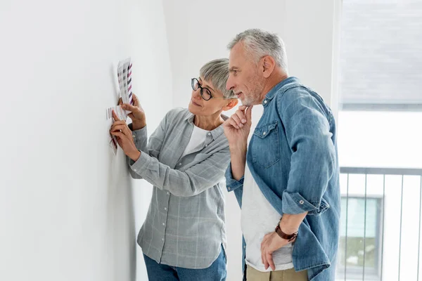 Pensive man and mature woman looking at palette in new house — Stock Photo