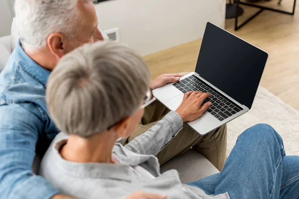 Vista recortada de hombre y mujer maduros utilizando el ordenador portátil en la nueva casa - foto de stock